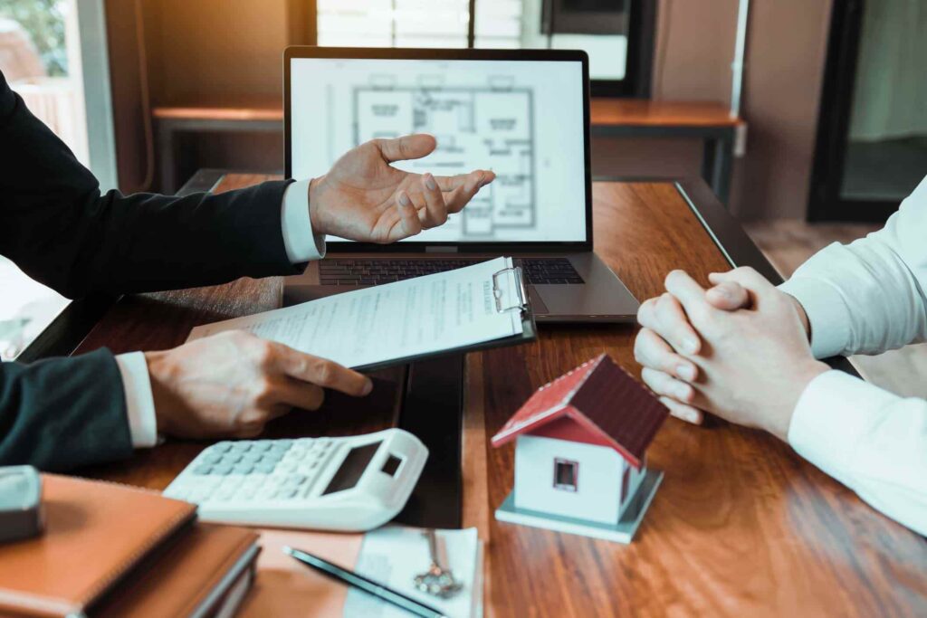 Insurance brokers sitting in an office, pointing to an insurance contract and explaining details to a pair of attentive customers.