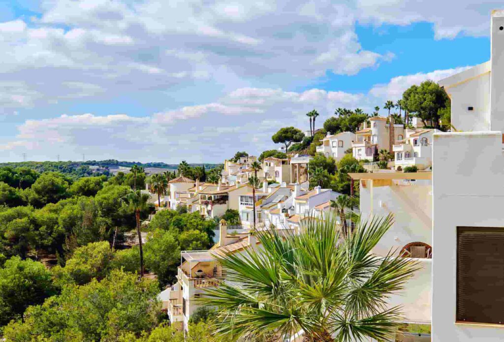 Spanish-style villas with terracotta roofs and balconies, surrounded by palm trees and lush greenery